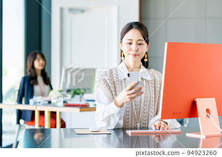 A young business woman looking at a smartphone in the office 94923260