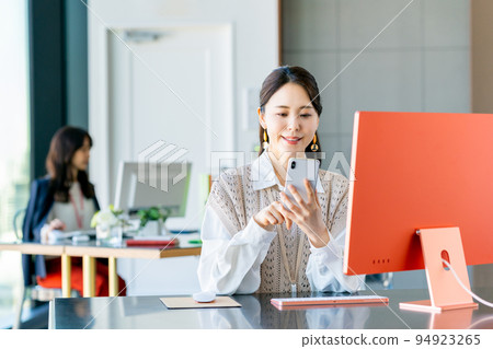 A young business woman looking at a smartphone in the office 94923265