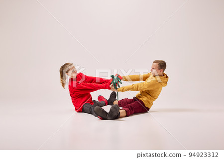 Emotional young couple, boy and girl in bright warm homewear having fun isolated on light background. Retro, vintage, dance, holidays, party concept 94923312
