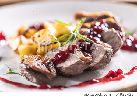 Culinarily prepared duck breast with baked potatoes and cranberry cauce. Culinarily prepared duck breast with baked potatoes and cranberry cauce. 94923423