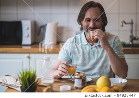 Mature man having breakfast and looking contented and peaceful Mature man having breakfast and looking contented and peaceful 94923447