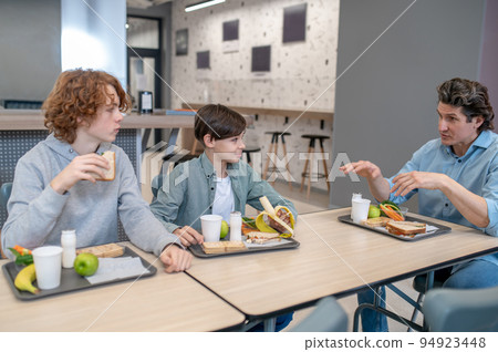 Pupils communicating with their schoolteacher at lunch Pupils communicating with their schoolteacher at lunch 94923448