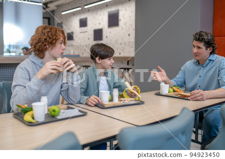 Pupils having lunch with their schoolteacher in the canteen Pupils having lunch with their schoolteacher in the canteen 94923450