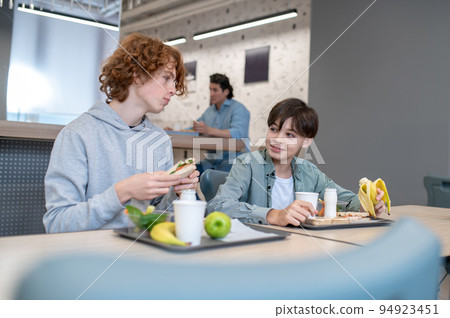 Two pupils eating lunch in the school canteen Two pupils eating lunch in the school canteen 94923451