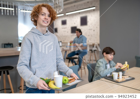 Cheerful pupil posing for the camera in the school canteen Cheerful pupil posing for the camera in the school canteen 94923452
