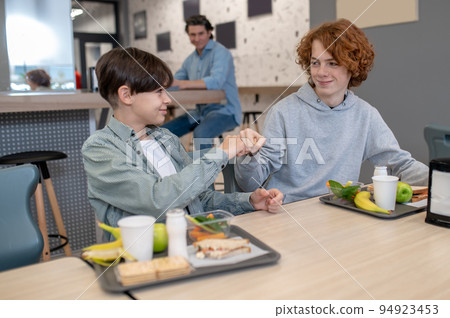 Schoolchildren greeting each other in the canteen Schoolchildren greeting each other in the canteen 94923453