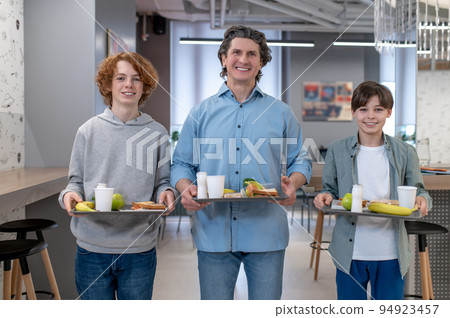 School boys and their teaher having lunch together at school canteen School boys and their teaher having lunch together at school canteen 94923457
