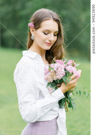 Young girl stand at park background with bouquet of  pink spireya flowers 94923690