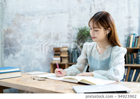 Young woman studying with earphones Young woman studying with earphones 94923902