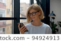 Woman holding smartphone, reading a message. Attractive blonde manager portrait on background of 94924913