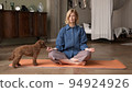 Woman doing breathing exercises, yoga practicing. Blonde attractive physical trainer at home 94924926