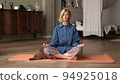 Woman doing breathing exercises, yoga practicing. Blonde attractive physical trainer at home 94925018