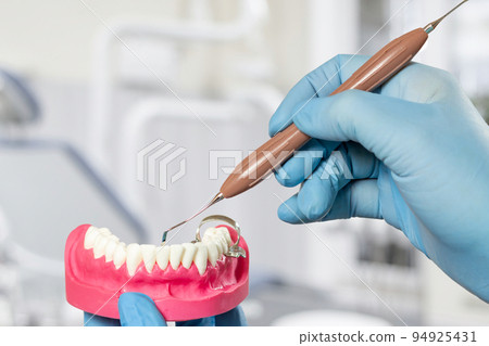 Dentist's hands with layout of the human jaw and dental instrument. Dentist's hands with layout of the human jaw and dental instrument. 94925431