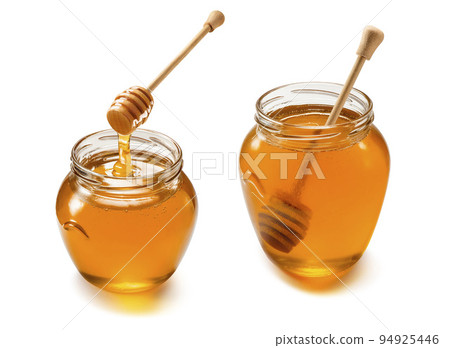 Two glass jars with liquid honey set isolated on white background. Wooden dippers 94925446