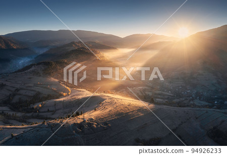 Aerial view of mountains and hills in low clouds at sunrise Aerial view of mountains and hills in low clouds at sunrise 94926233