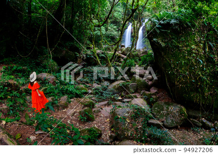 Beautiful woman in red dress in front of the Sapan Waterfall, Khun Nan National Park, Boklua District, Nan Province, Thailand. 94927206