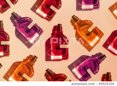 Pattern of different perfume bottles on a pastel beige background in the sunlight. Flat lay, top view. Luxury presentation mockup. Red, yellow and orange samples of aroma water 94928108