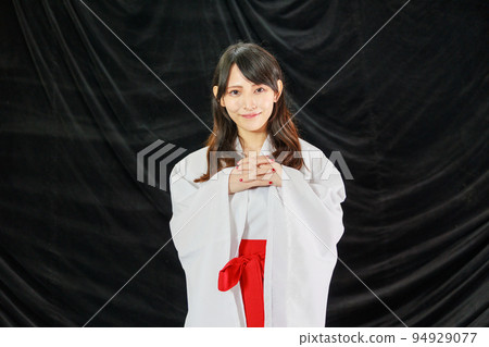 Japanese woman wearing shrine maiden clothes in black background Japanese woman wearing shrine maiden clothes in black background 94929077