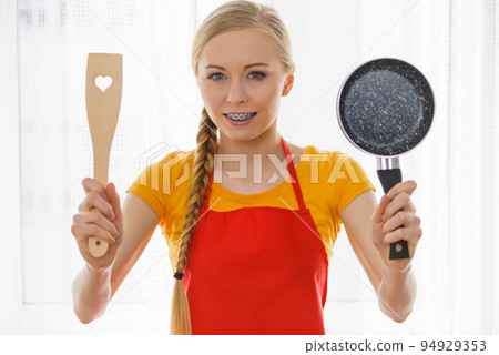 Woman holding cooking pan and spatula 94929353