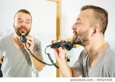 Man shaving trimming his beard Man shaving trimming his beard 94929368