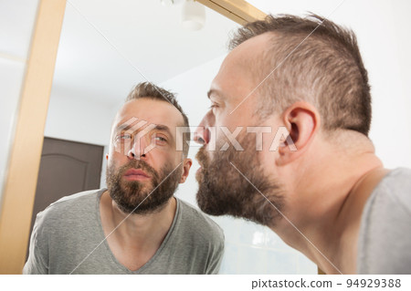 Man looking at beard in mirror 94929388