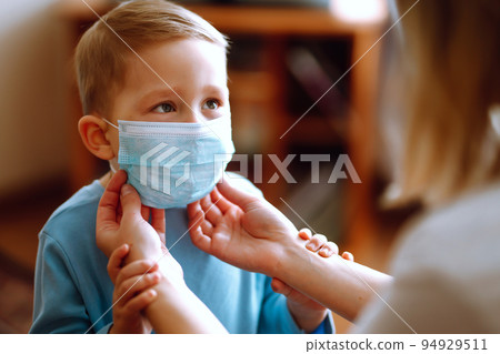 Little boy and mom in medical mask. Mother puts on her baby sterile mask. Child, wearing face mask. 94929511