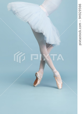 Cropped image of female legs, ballerina in tutu and pointe standing on tiptoe isolated isolated over blue studio background 94929566