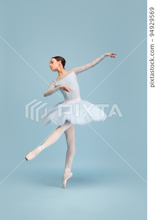 Portrait of tender young ballerina dancing, performing isolated over blue studio background. Graceful dance 94929569