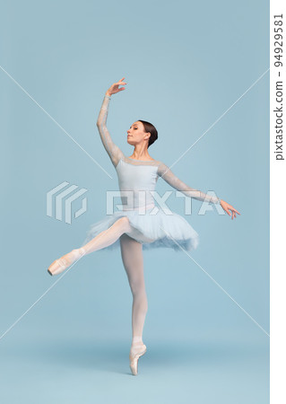 Portrait of tender young ballerina dancing, performing isolated over blue studio background. Graceful theatrical performance Portrait of tender young ballerina dancing, performing isolated over blue studio background. Graceful theatrical performance 94929581