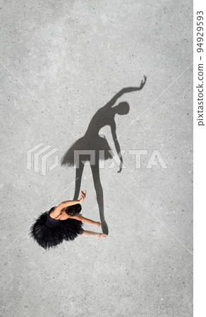 Portrait of young ballerina in black dress performing isolated over grey wall background. Top view. Shadow element. Dreams 94929593