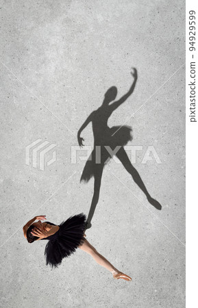Portrait of young ballerina in black dress dancing isolated over grey wall background. Top view. Shadow element 94929599
