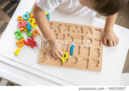 Male kid playing with wooden eco friendly alphabet letters board on table top view intellectual game 94929807