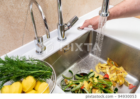 Turning on a disposer in a modern kitchen to remove food waste 94930053