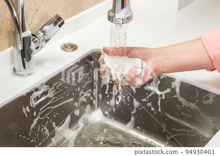 Sponge in a woman's hand is washed off with tap water Sponge in a woman's hand is washed off with tap water 94930401