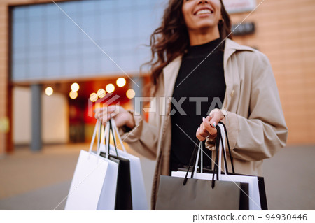 Young woman with shopping bags near mall. Spring Style. Consumerism, purchases, shopping, lifestyle. Young woman with shopping bags near mall. Spring Style. Consumerism, purchases, shopping, lifestyle. 94930446