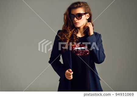 beautiful young girl wearing a jacket, shirt and pants posing on a gray background. studio photo. beautiful young girl wearing a jacket, shirt and pants posing on a gray background. studio photo. 94931069