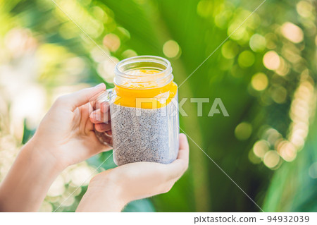Chia seed pudding with almond milk and fresh mango topping in hand Chia seed pudding with almond milk and fresh mango topping in hand 94932039
