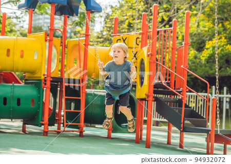 Funny kid boy having fun with chain swing on outdoor playground. child swinging on warm day. Active leisure with kids. Boy wearing casual colorful school kid clothes Funny kid boy having fun with chain swing on outdoor playground. child swinging on warm day. Active leisure with kids. Boy wearing casual colorful school kid clothes 94932072