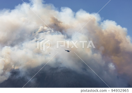 Wildfire Service Helicopter flying over BC Forest Fire and Smoke on the mountain near Hope 94932965