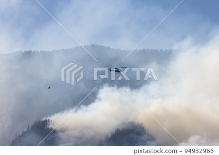 Wildfire Service Helicopter flying over BC Forest Fire and Smoke on the mountain near Hope 94932966