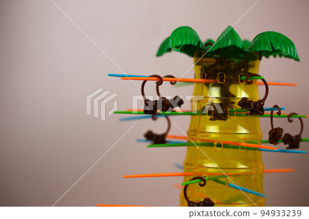 Board game with monkeys and palm tree. Plastic set for children to play. Pulling sticks one at a time until all monkeys fall 94933239
