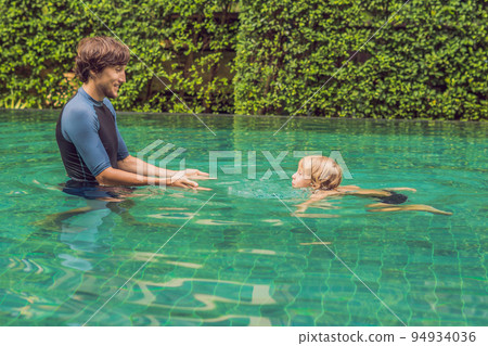 Male instructor swimming for children teaches a happy boy to swim in the pool 94934036