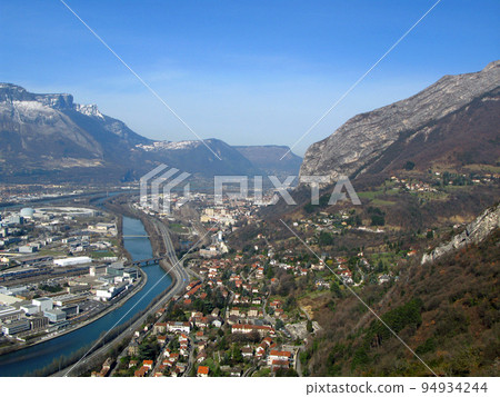 Grenoble. View of city from above from great height from the Bastille fortress. Mountains with snow, Isere river, roofs of houses, roads. France Grenoble. View of city from above from great height from the Bastille fortress. Mountains with snow, Isere river, roofs of houses, roads. France 94934244