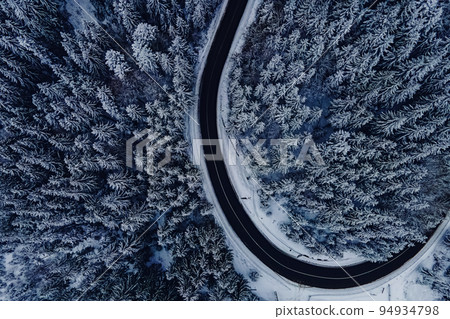Pine trees covered with snow. Highway through the winter forest, aerial drone view 94934798