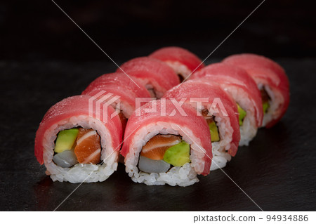 Sushi roll Maguro with tuna, shrimp, salmon, smoked eel, avocado, philadelphia cheese on black background. Sushi menu. Japanese food. Sushi roll Maguro with tuna, shrimp, salmon, smoked eel, avocado, philadelphia cheese on black background. Sushi menu. Japanese food. 94934886