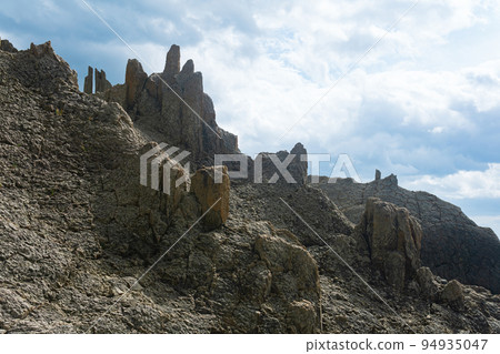 majestic rocks from volcanic columnar basalt against the sky, natural landscape of Kunashir island 94935047