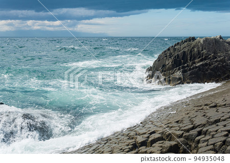rocky seashore formed by columnar basalt against the surf, coastal landscape of the Kuril Islands rocky seashore formed by columnar basalt against the surf, coastal landscape of the Kuril Islands 94935048