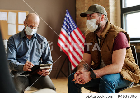 Mature counselor making notes while stressed man describing his problems 94935390