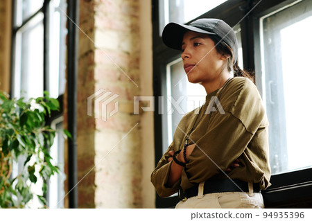 Side view of young upset woman with post traumatic syndrome standing by window Side view of young upset woman with post traumatic syndrome standing by window 94935396