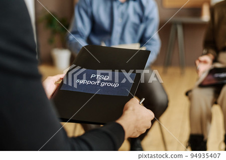 Selective focus on black folder with sticker saying PTSD support group Selective focus on black folder with sticker saying PTSD support group 94935407
